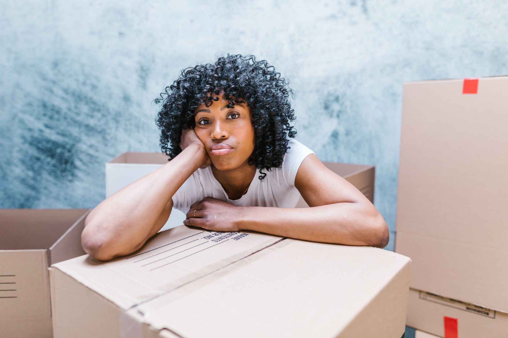 A frustrated looking woman is surrounded by packed boxes while she contemplates how to move on after divorce.