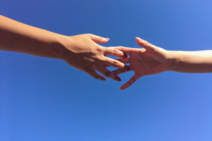 Hands reaching out toward each other in front of blue background, finding the right divorce expert for you.