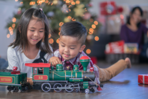 Boy and girl playing with green train on Christmas morning in front of Christmas Tree, What I Wish All Kids Of Divorced Parents Thought About The Holidays