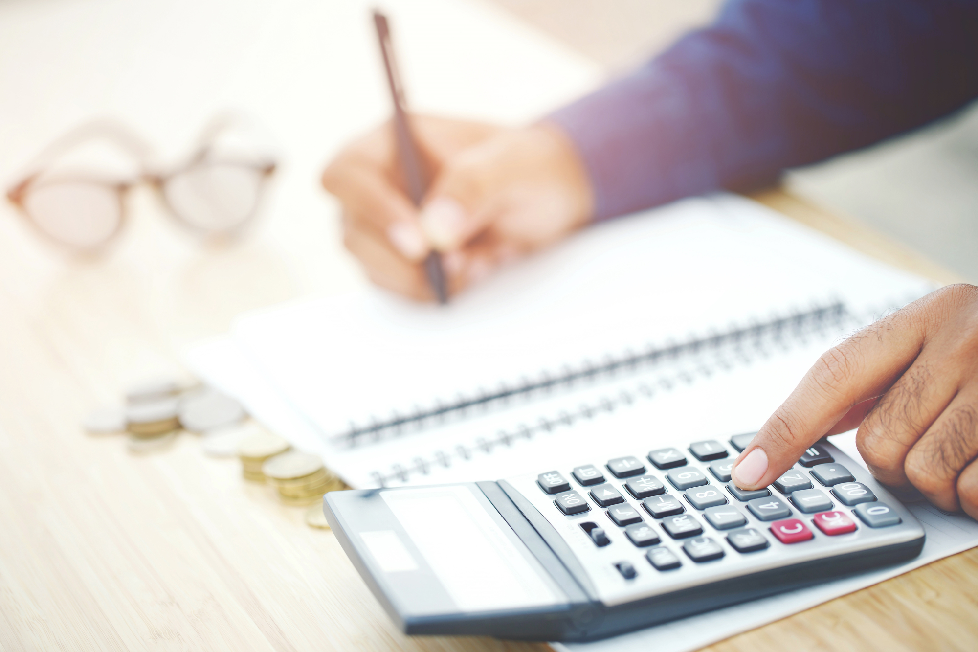 Person calculating budget on paper with a calculator.