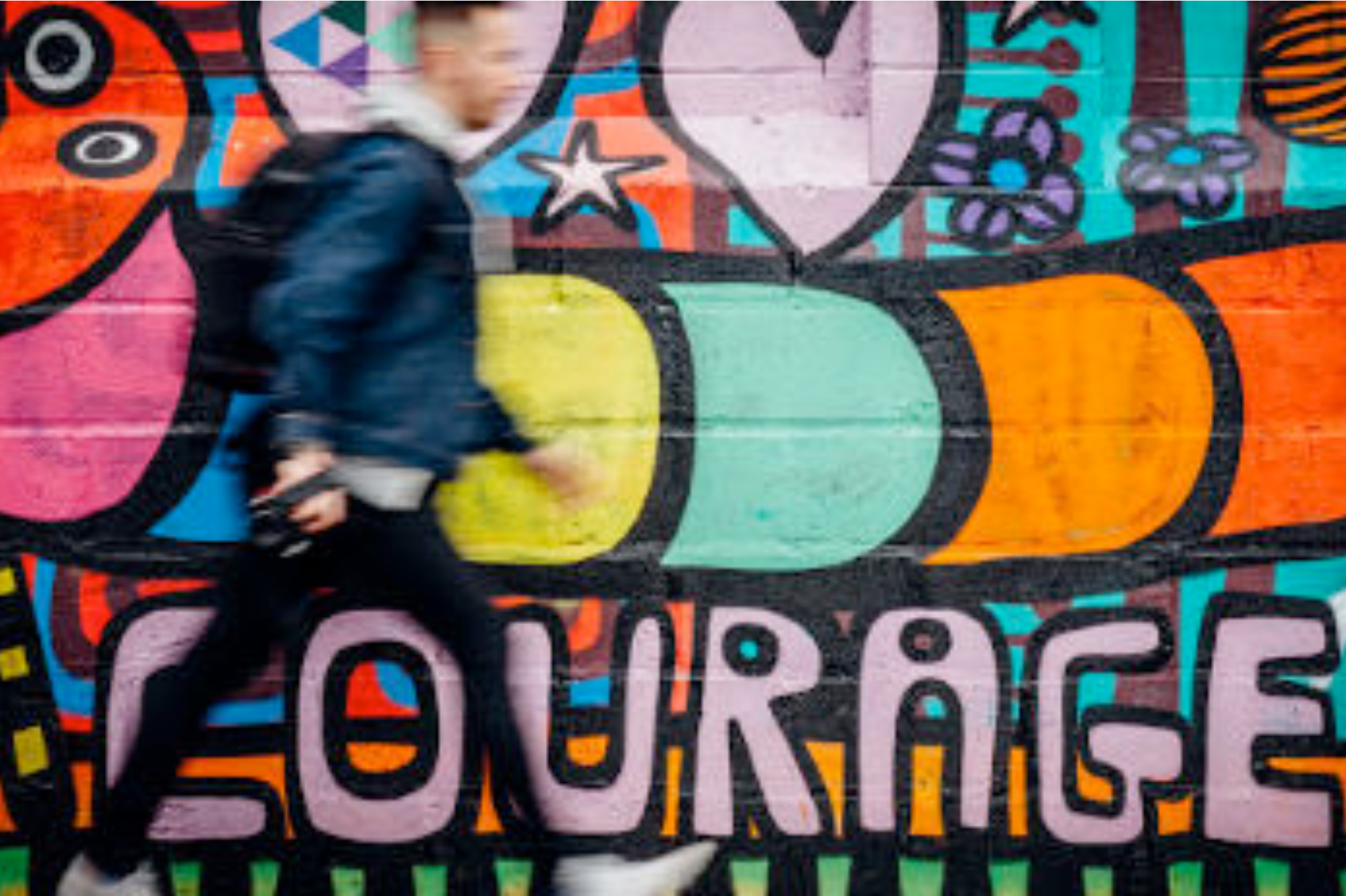 Man walking past a mural of courage as a reminder that&#039;s what healing from divorce requires.
