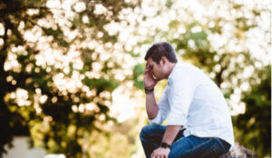 Man sitting on a bench struggling with overcoming his divorce misery.