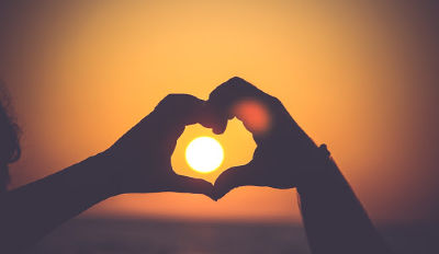 Couple making a heart over the setting sun because they&#039;ve found the love of their life.