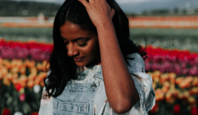 Woman holding her head in a field of flowers as she contemplates coping with her divorce.