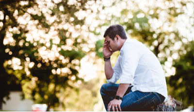 Man sitting on a bench and holding his head while struggling getting divorced.