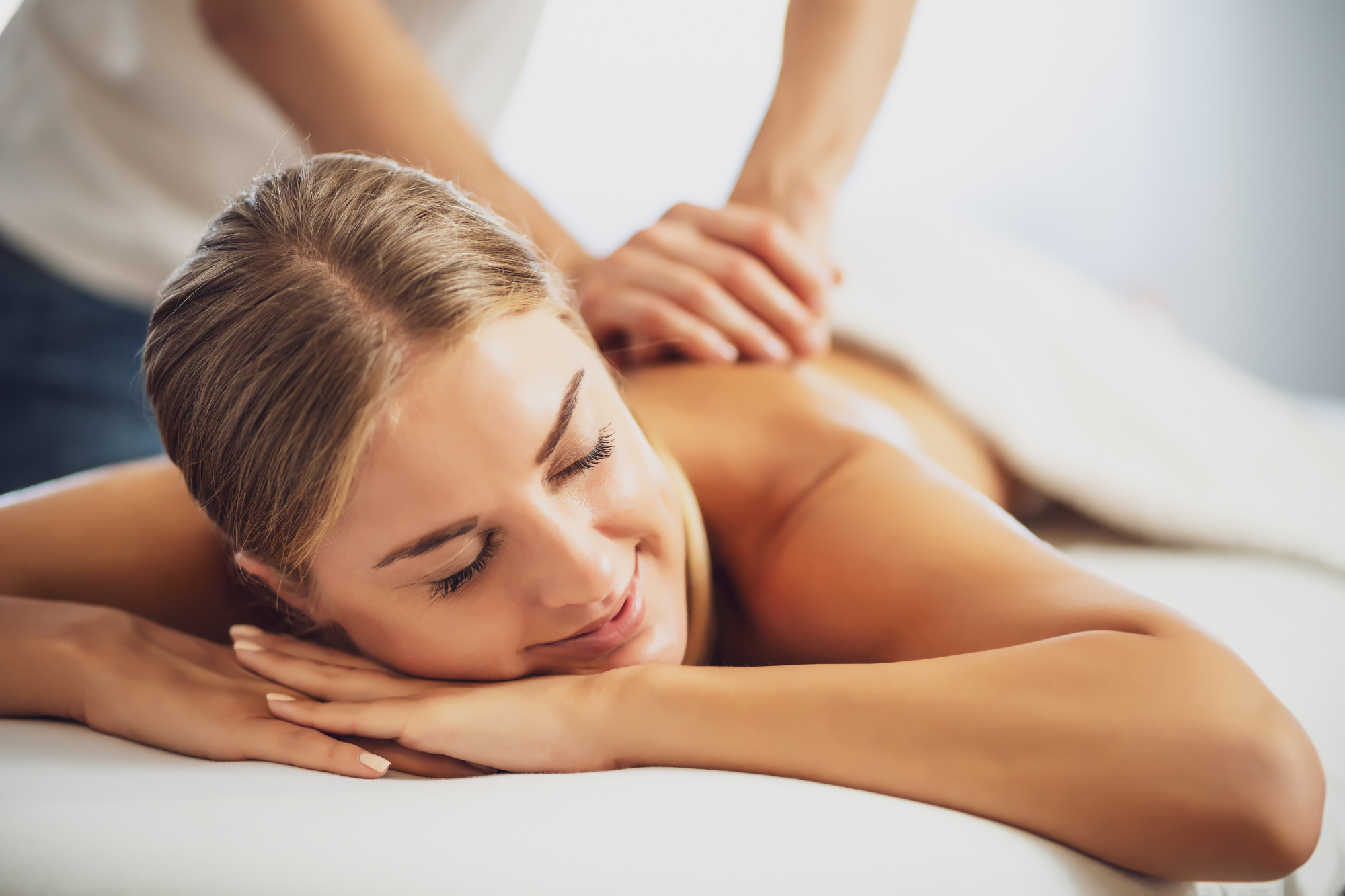 Woman smiling during massage on massage table. Can a massage per day keep divorce away, yes.