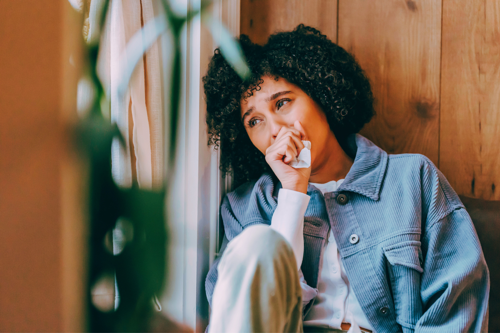 Woman in tears. wearing a blue jacket, sitting on floor looking out window. The Secret Grief of Divorce you Never Talk About