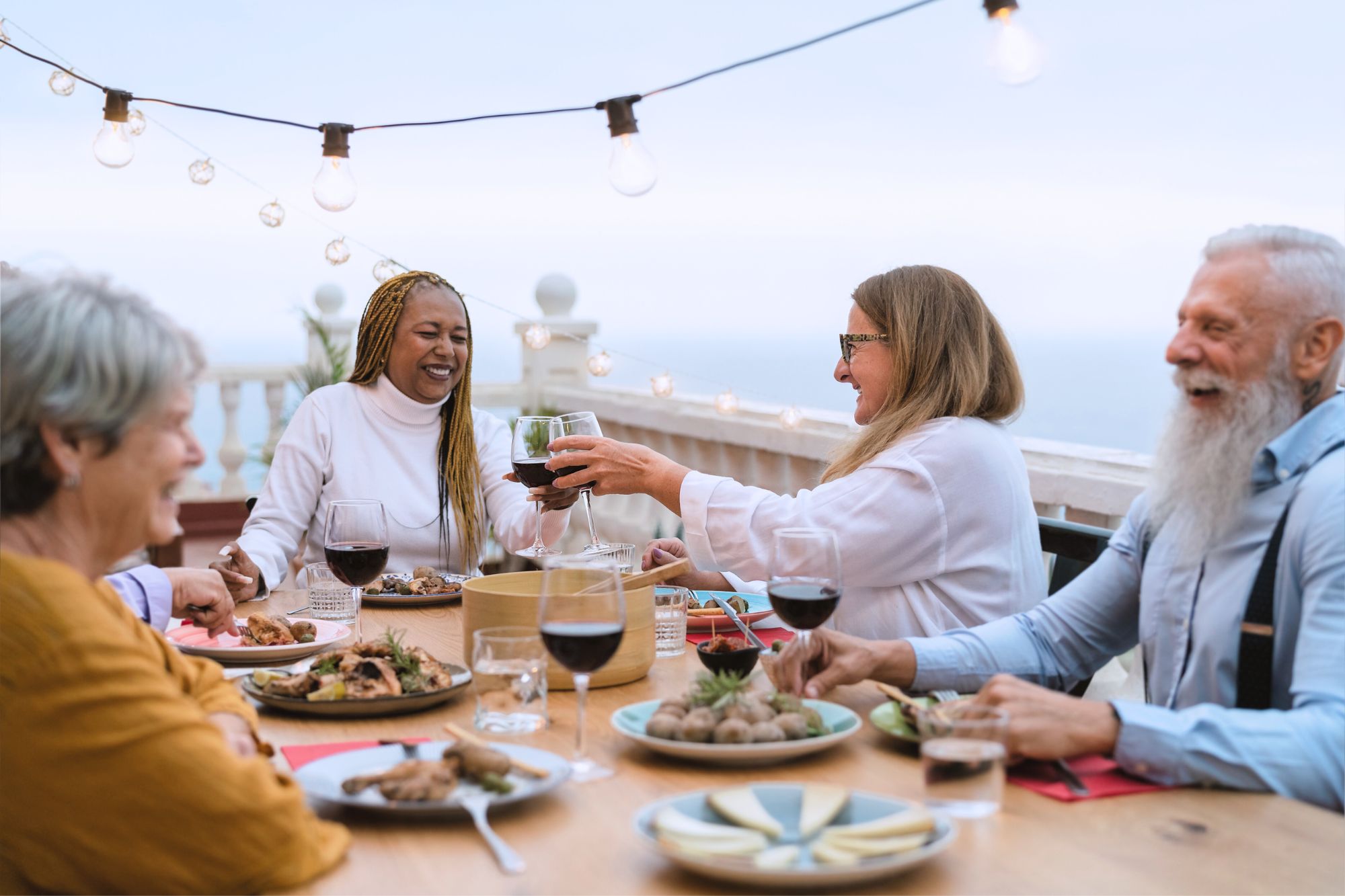 Diverse people are enjoying dinner and drinks outdoors as they discuss how to deal with losing your friends, and making new ones, post-divorce.