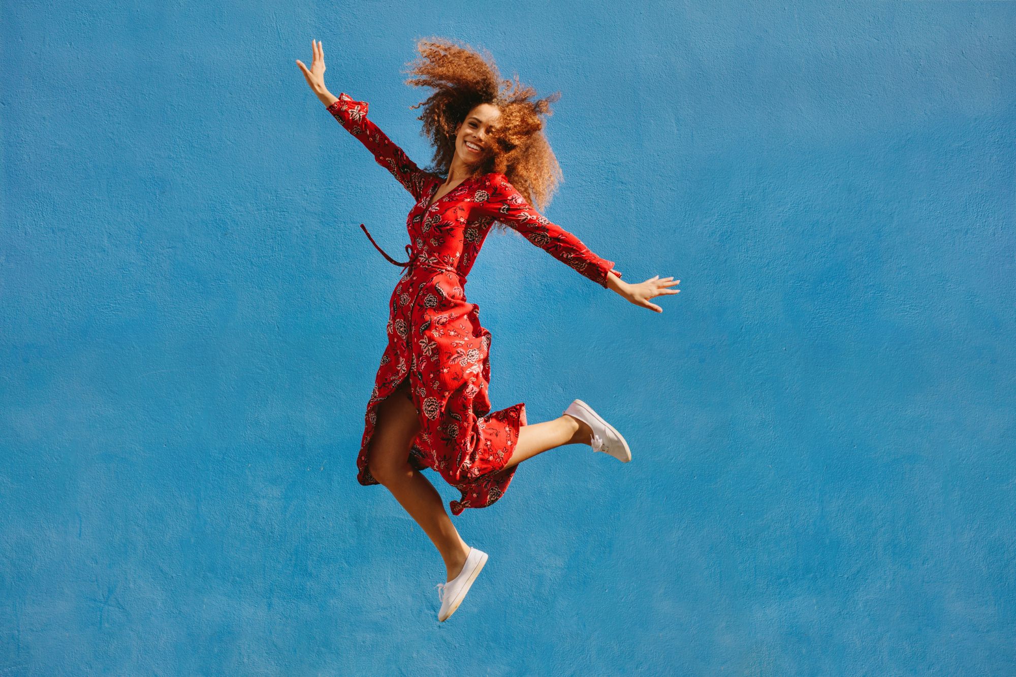 Woman in red dress jumping for joy as she is learning How To Be Happy As You’re Healing After Divorce.