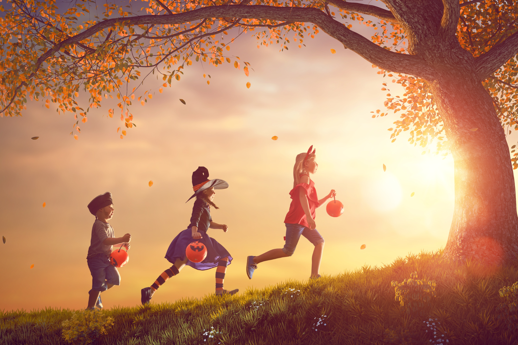 Children in costumes trick or treating at sunset, halloween