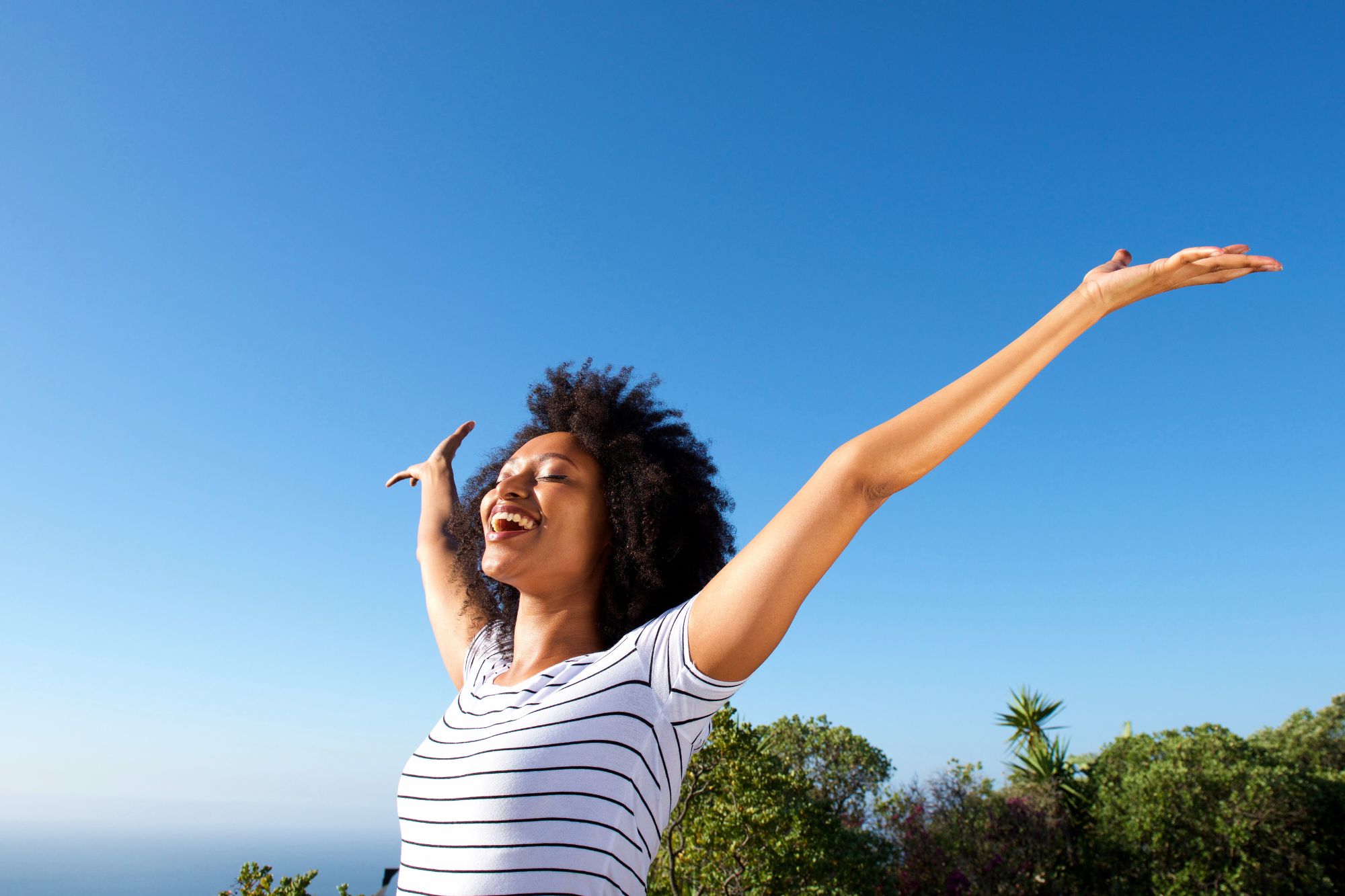 Joyful woman with her arms lifted in celebration as she considers the 5 tips for a happier life after divorce