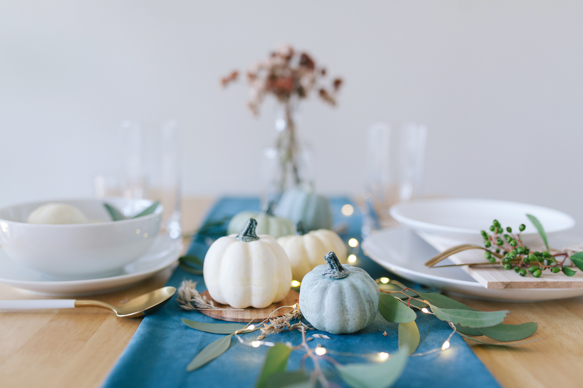 Holiday table set with white plates, a blue runner, white and blue pumpkins, and flowers. 21 Tips To Survive Divorce And The Holidays.