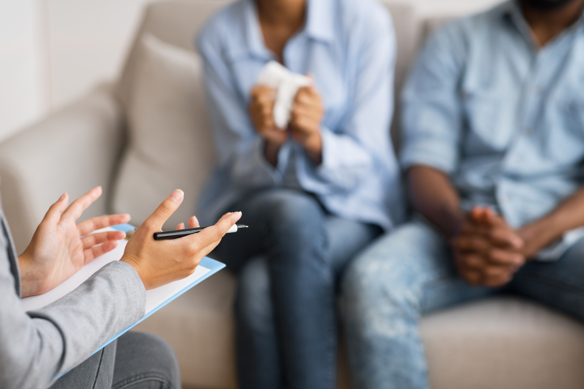 couple oin blues, sitting on couch, listening to therapist counseling. Which marriages survive infidelity, how to tell if yours is one of them.