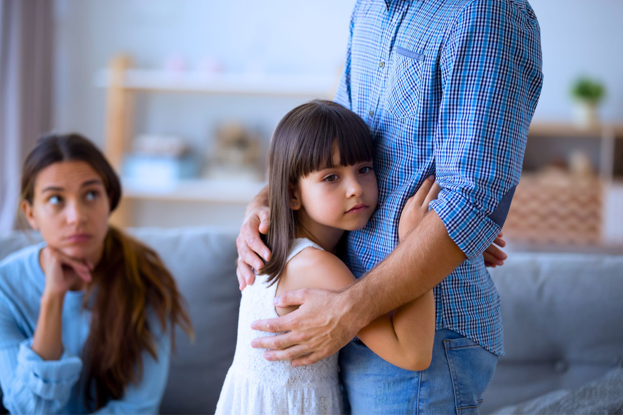 Little girl hugging father as mother looks concerned as she contemplates how to win your next co-parenting conversation