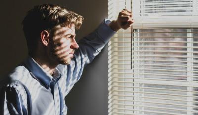 Man looking out window and wondering what causes infidelity in marriage.