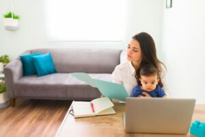 Mom holds baby on lap while working at computer as she deals with what life after divorce with a baby is really like.