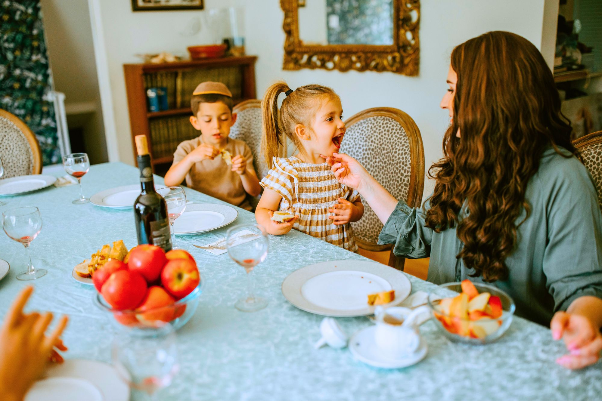 Woman at dinner table with young boy and girl, contemplating How To Survive Co-Parenting With an Ex AND Their New Love