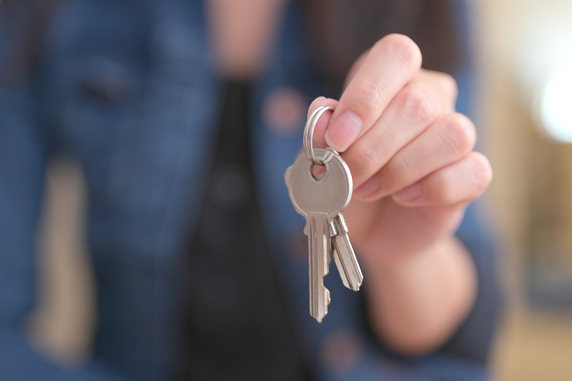 Woman in blue top, holding keys as she contemplates how to know when to get a divorce.