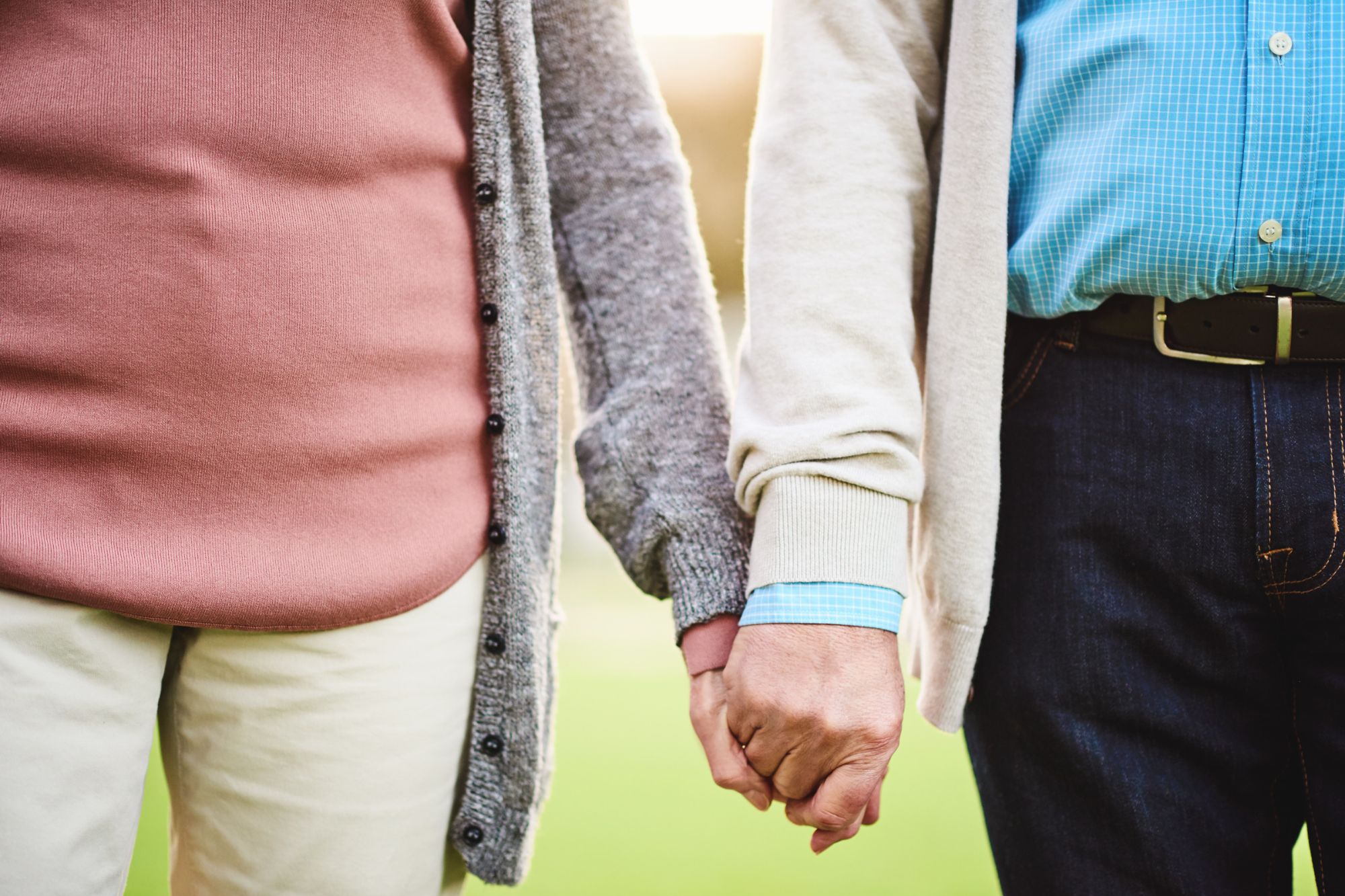 Close up of an older couple walking and holding hands after they learned how to handle an unhappy marriage and find happiness again.