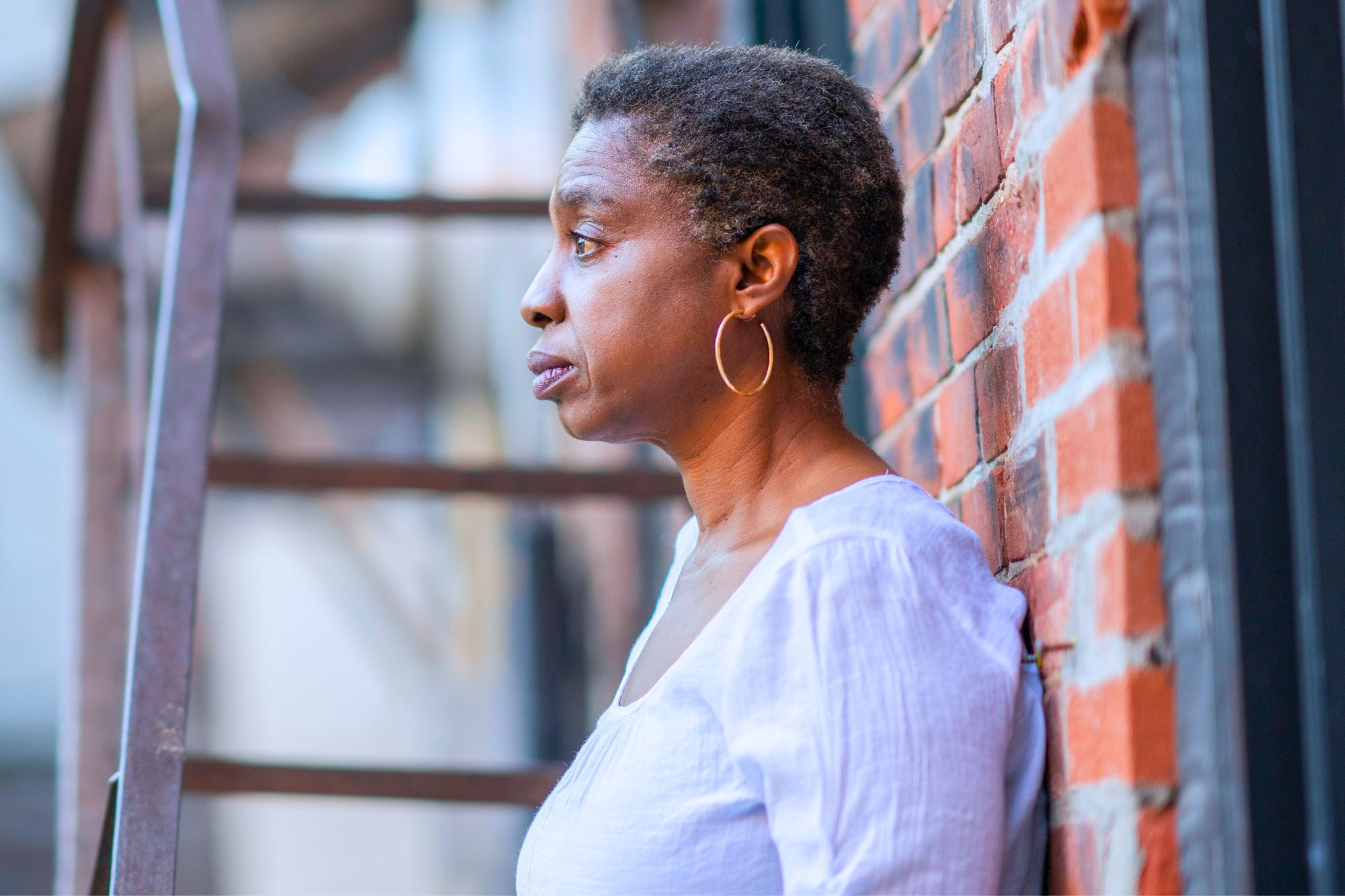 Woman standing against brick wall contemplating what her life after divorce at 50 is really like.