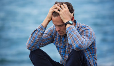 Man holding his head wondering if surviving an unhappy marriage is even possible.