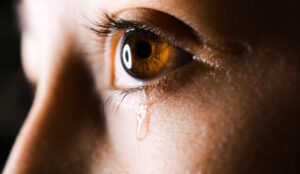 Tear falling from a woman’s eye as she struggles to deal with marital infidelity.