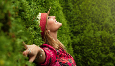 Woman leaning against a hedge enjoying the happiness in life that she’s found.