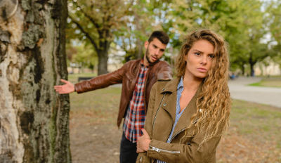 Couple near a tree arguing about how to handle co-parenting.