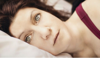 Staring woman lying with her head on a pillow struggling with healing after a divorce or breakup.