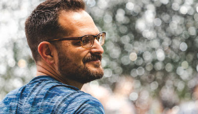 Man wearing glasses smiling because he knows his happy life will begin when you chooses it.