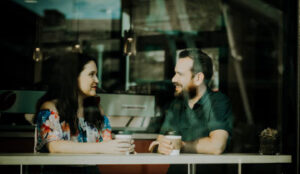 Man and woman sitting in a coffee shop exploring how self-awareness can affect communication.