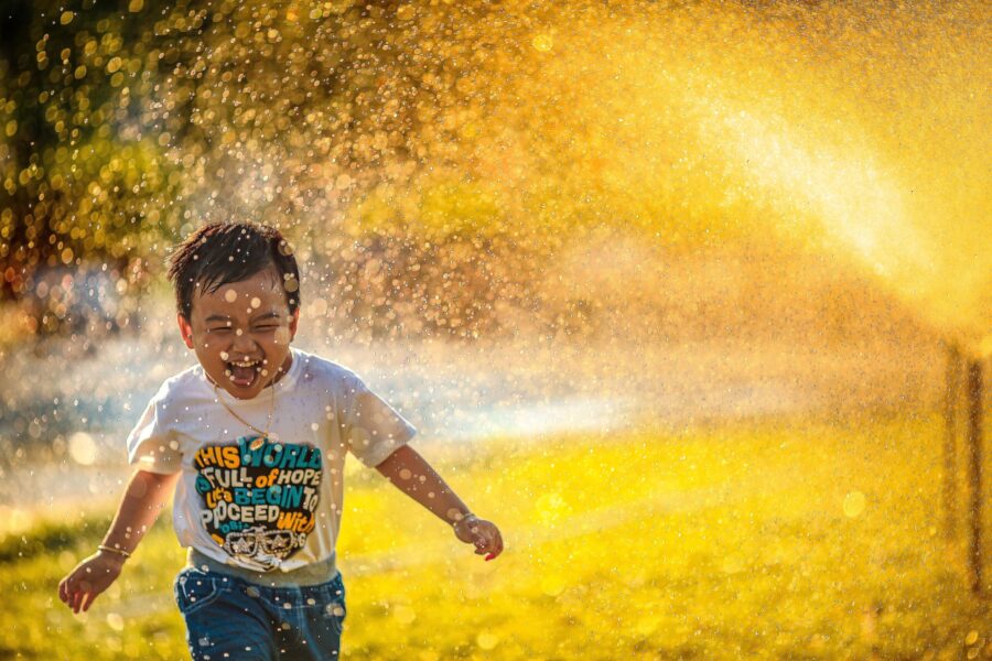 Little boy joyfully playing in a sprinkler.