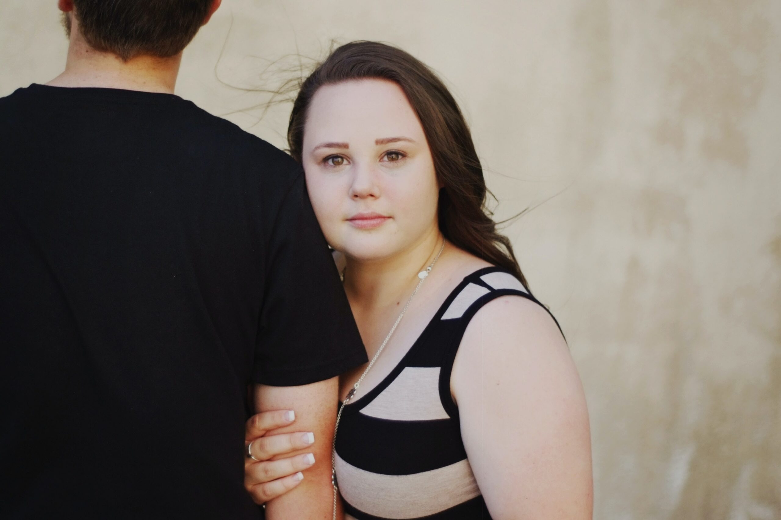 Woman holding her husband’s arm and contemplating the keys for fixing an unhappy marriage.