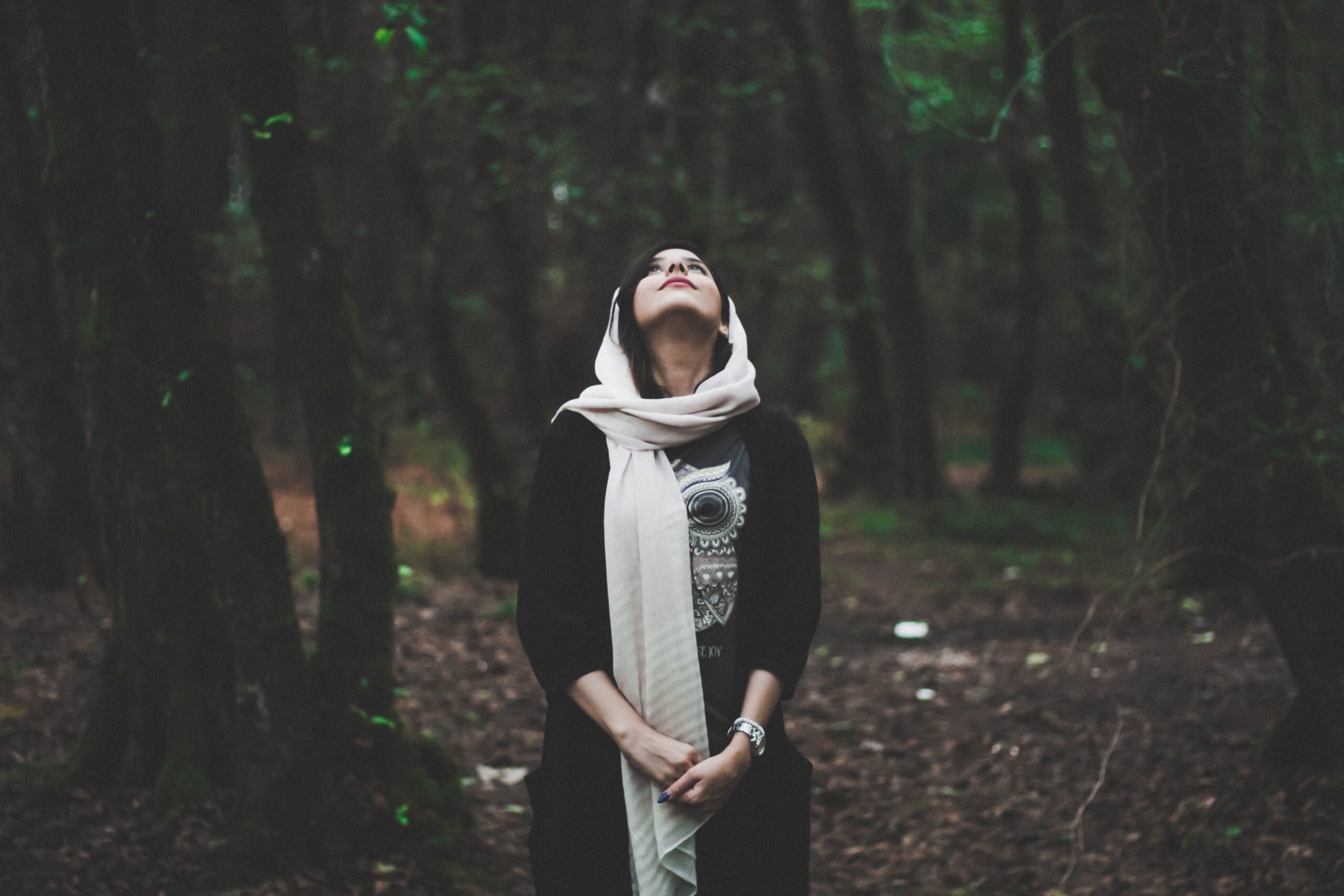 Woman looking up while standing in a forest and contemplating her self-awareness.