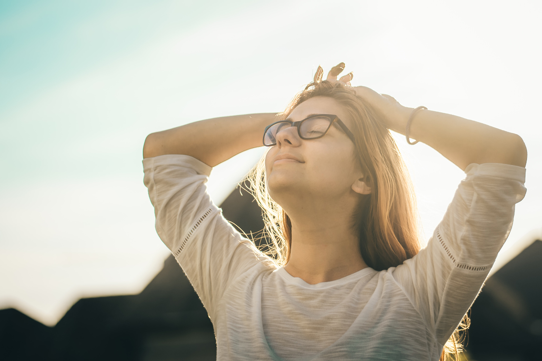 Happy woman standing with her face to the sun enjoying its warmth.