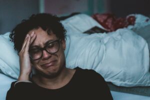 Woman sitting on the floor next to her bed crying about her miserable marriage