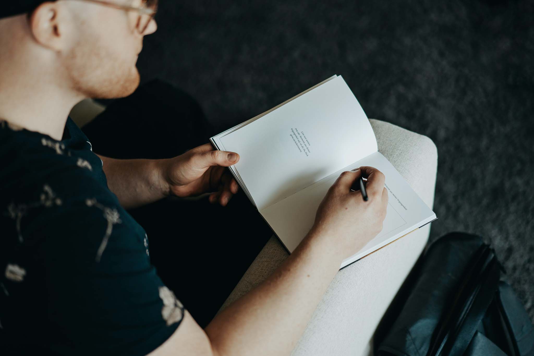 Man with pen poised to write, pauses to consider a journal prompt for self-awareness.