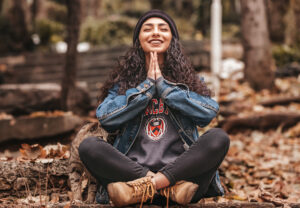 Woman meditating about improving her self-awareness in a forest with a cat by her side.