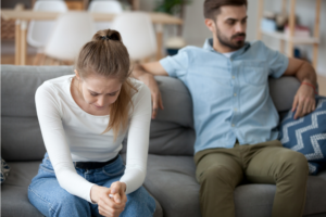 Woman sitting next to her angry husband crying.