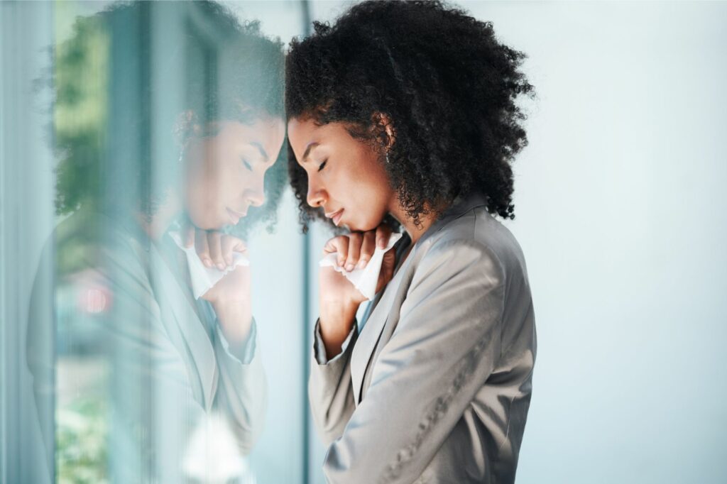 Woman leaning her head on a window at work wondering how to get over her emotional affair.