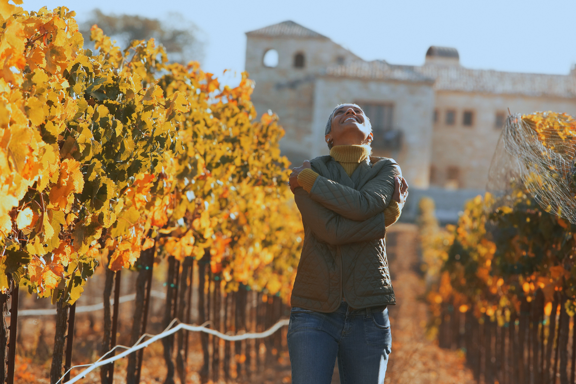 Woman hugging herself in vineyard during the fall