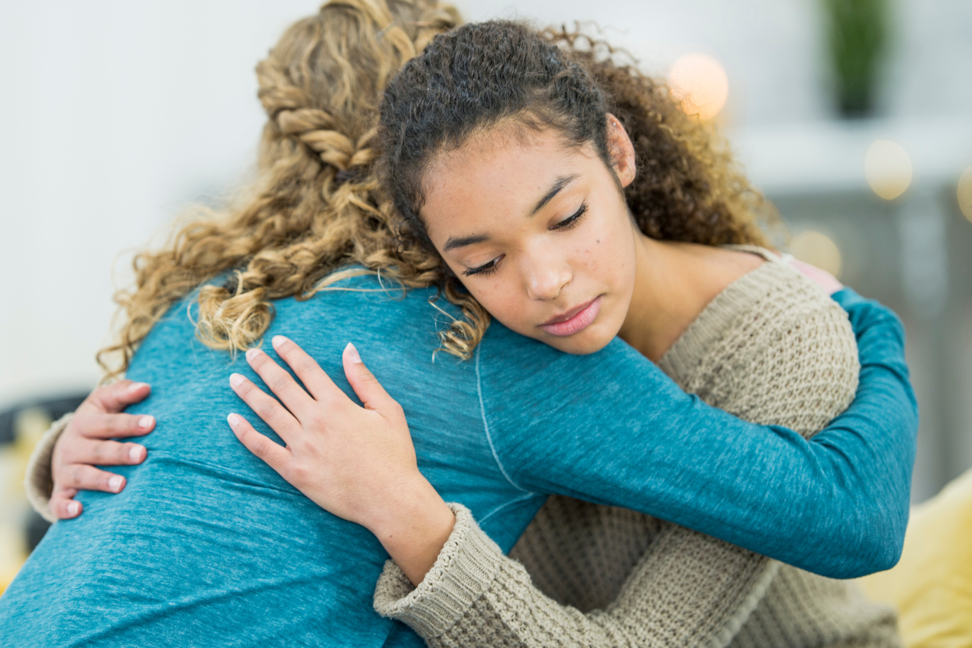 Mother in blue hugging teenage daughter